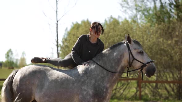 Female Equestrian with Long Hair Mounts Grey Horse During Training
