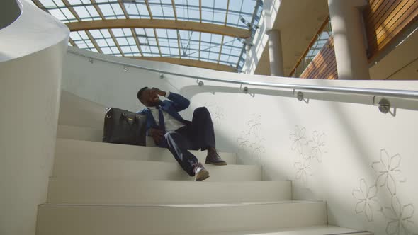 African Man in Formal Suit and Tie Sitting on Indoors Office Stair Relaxing