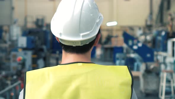 Factory Worker with Safety Hard Hat Walking Through Industrial Facilities