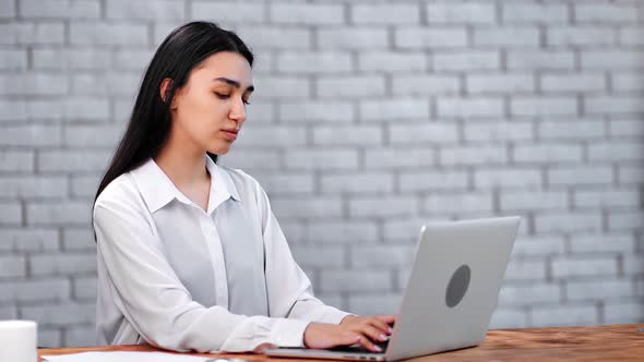 Pensive Asian Businesswoman Chatting on Laptop at Office