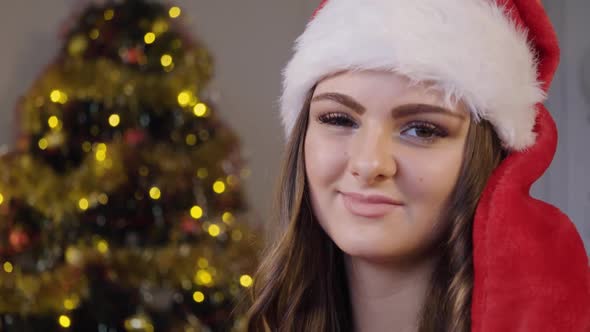 A Young Beautiful Woman in a Christmas Hat Smiles at the Camera - Closeup