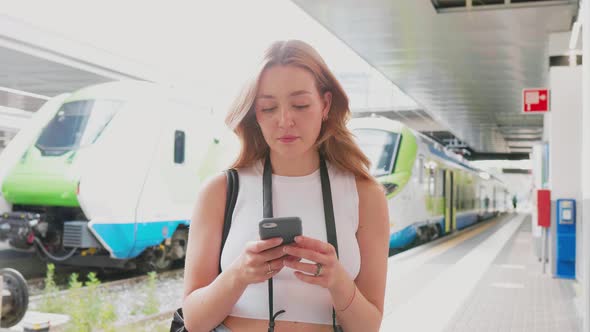 Young woman using smartphone looking camera positive and trustful in future