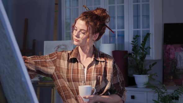 Art Female with Paintbrush in Hair Enjoying Hot Coffee After the Creative Process Happy Young Woman
