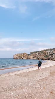 Happy Young Woman in a Raincoat Runs To the Sea Bottom View