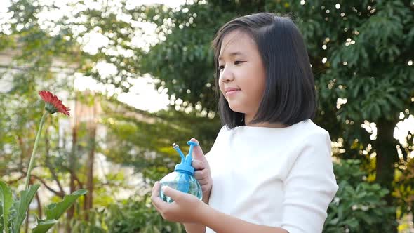 Beautiful Asian Girl Watering A Red Flower In The Garden