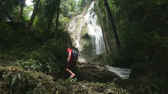 Man Walking In Front Of A Waterfall