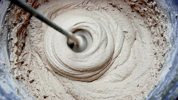 Mixing the Plaster Mixture in a Bucket with a Drill