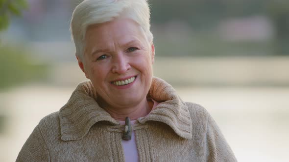 Happy Middle Aged Elderly Grey Haired Woman Looking at Camera Posing Standing Outdoors