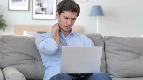 Handsome Young Man with Neck Pain Working on Laptop