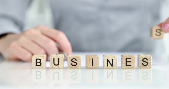 Business Person Puts Cube with Letter s in Word Business