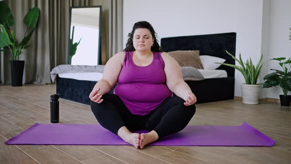 Body Positive Brunette Meditates on Sports Mat on Floor