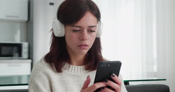 Sad Woman with Headphone Reading Bad News on Smartphone