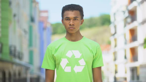 Serious Mixed-Race Teen Male in T-Short With Recycling Symbol Looking on Camera