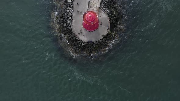 Top down view fly by of people walking around The Poolbeg Lighthouse.