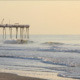 Surfers Catching Waves Near Pier at Sunrise - VideoHive Item for Sale