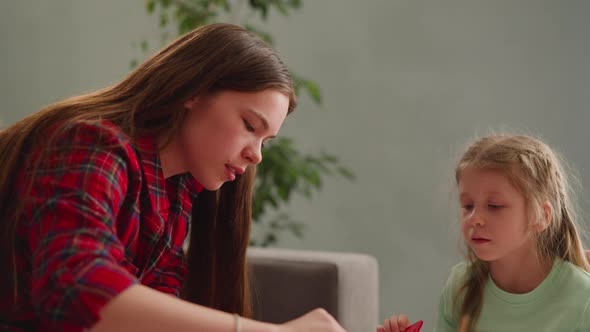 Concentrated Girl Looks at Long Haired Sister Mixing Colors