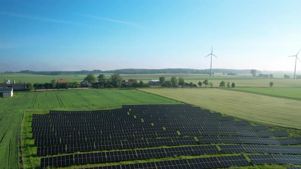 Solar Panels And Wind Turbines In A Green Field At Daytime - aerial drone shot