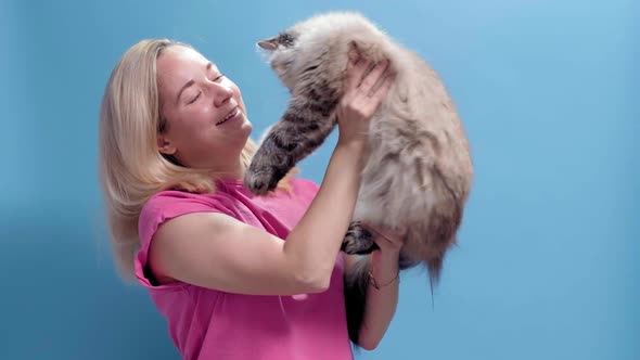 A Young Caucasian Blonde Woman Holds a Cat in Her Hands