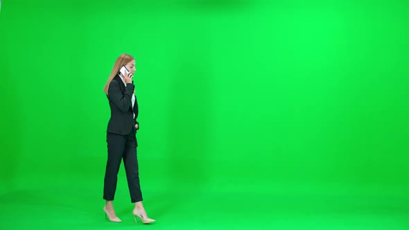 Businesswoman in a Suit Walking on Chroma Key Background Female Using Smartphone and Talking on a