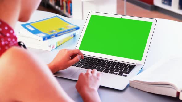 School girl using laptop in library