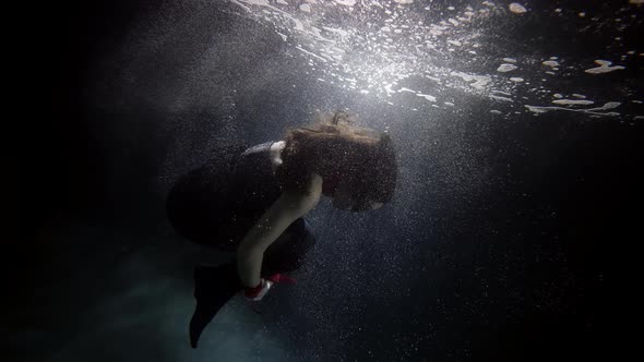 Graceful Woman Is Swimming Underwater in Pool or Aquarium Female Figure in Darkness