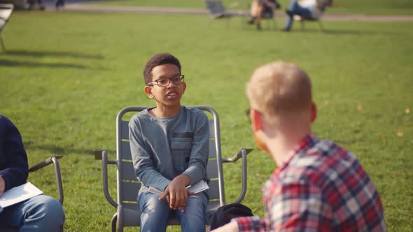 African Preteen Boy in Glasses Raising Hands and Answering Teacher Question at Outdoors Lesson