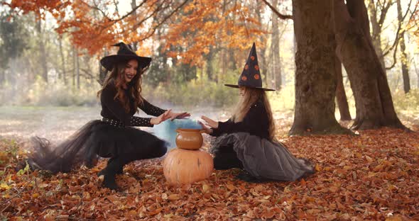 Beautiful Brunette Mom and Cute Little Daughter Looking Like Witches in Special Dresses and Hats in