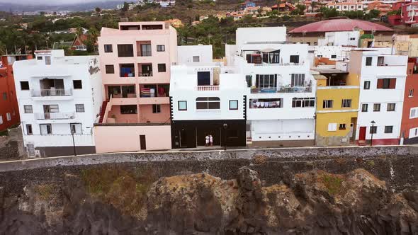 A Beautiful Girl and a Man in White Tshirts and Shorts Kiss Against a Wall in Puerto De La Cruz