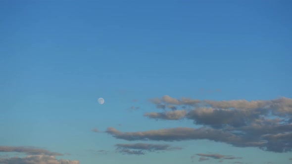 Time-lapse 4k, the full Moon rise up in the blue sky above the beautiful clouds