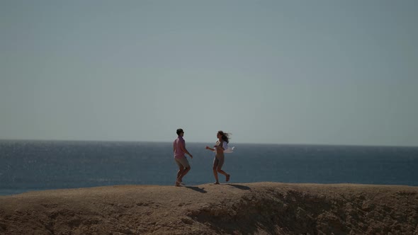 a Woman with Long Hair in a White Shirt and a Man in a Pink Tshirt Run Up to Each Other Hug and Spin