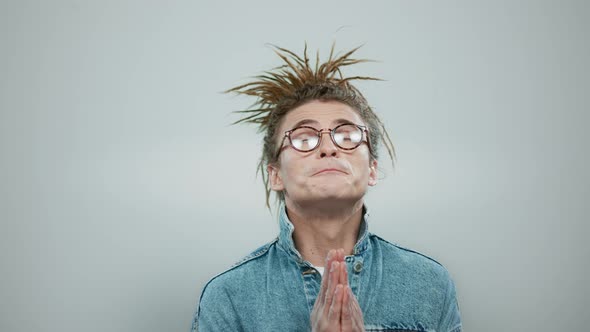 Stylish Man Praying in Studio. Serious Guy Holding Hands in Prayer Position