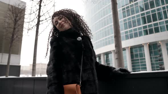 a Curlyhaired Middleaged Woman a Brunette in a Black Fur Coat Walking Alone in the City on a Cold