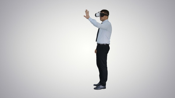 Young businessman using vr headset on gradient background.