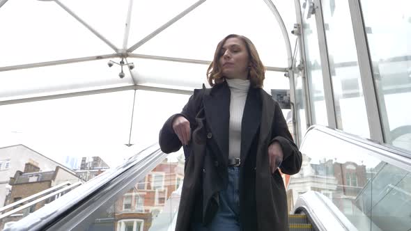 Slow motion shot of businesswoman on escalator looking at smartphone