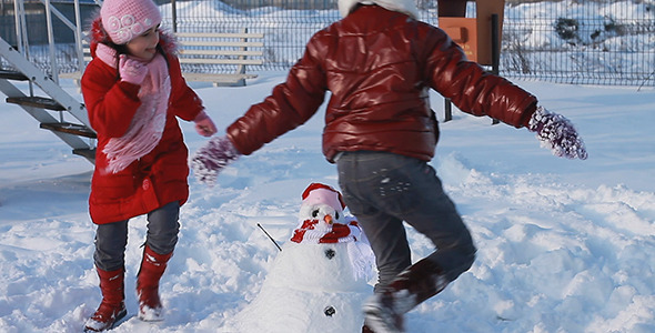 Happy Girls Running Around a Snowman