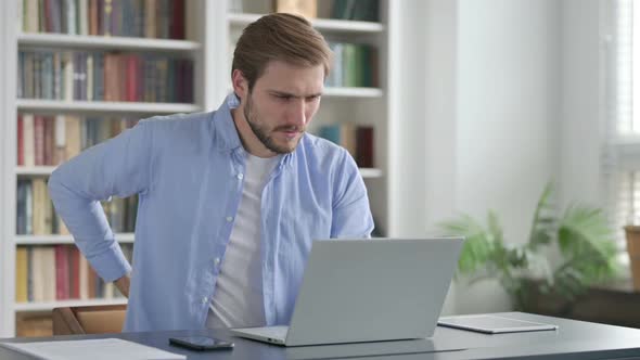 Man Having Back Pain While Using Laptop in Office