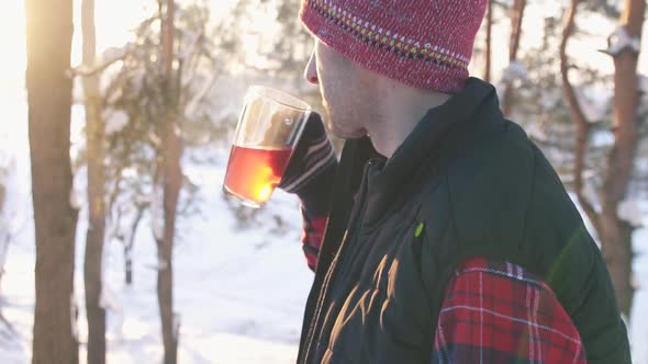 Guy in Winter Clothes Drinking Hot Mulled Wine at Sunset in Winter Forest Winter Fun