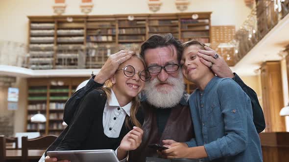 Grandfather with Grandchildren Cheerfully Spending their Time Together in the Library