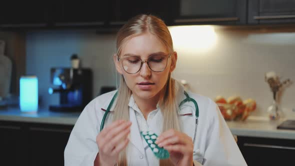 Video Call To Patient: Female Doctor in Medical Gown Looking To the Camera and Explaining How To