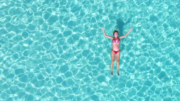 Aerial view of an attractive woman floating in turquoise sea