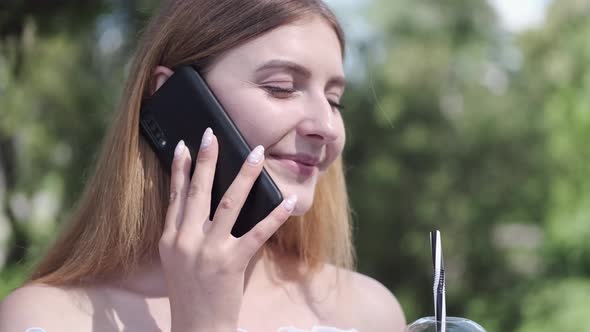 Happy Lady Is Talking By Phone and Drinking Takeaway Cocktail