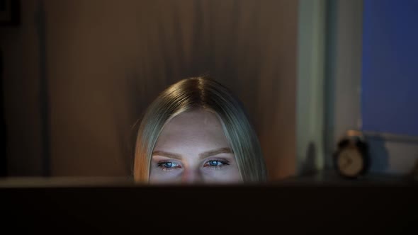 Woman Peeking Out Computer Monitor at Night. Crop View of Beautiful Female Sitting at Night at