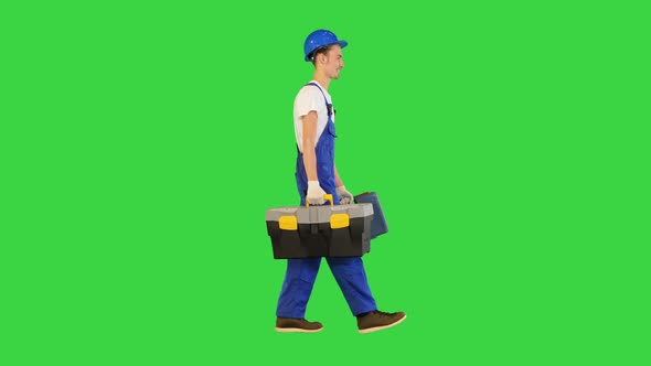 Young Construction Worker is Walking to you with His Two Toolboxes on a Green Screen Chroma Key