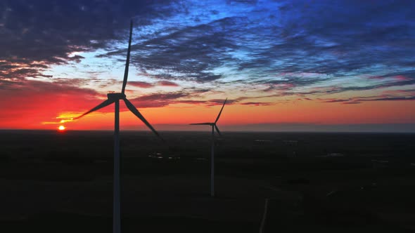 Sunset with wind turbines on farm field, aerial view