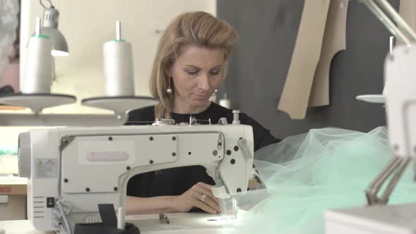 Blonde Beautiful Caucasian Female Sitting at Table with Sewing Machine in Classroom Working