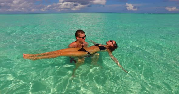 Young man and woman on honeymoon vacation enjoy life on beach on white sand background 