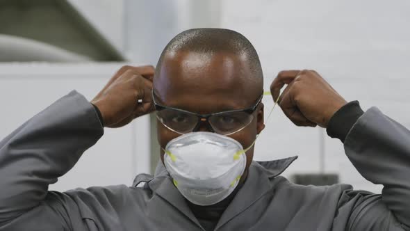 African American male car mechanic putting a face mask on