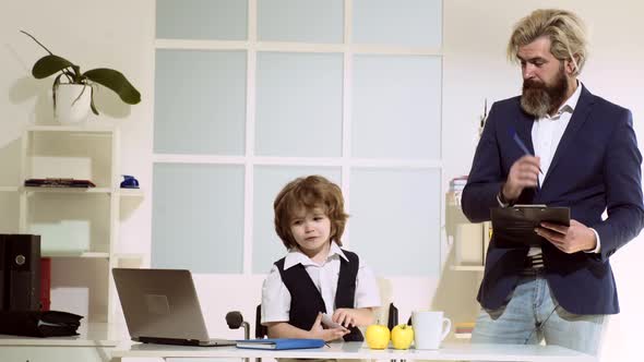 Little Boy Playing To Be Boss on a Business Desk in Office. Businessmans Crew Working with New