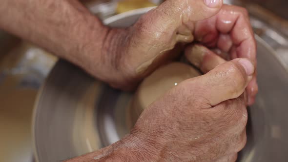 Potter's Hands Add Liquid to Clay with Their and Fingers Form Rounded Shape Using Potter's Wheel