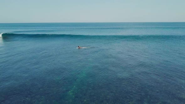Cinematic Aerial View Over a Surfer Riding a Breaking Wave in the Ocean at Summer.